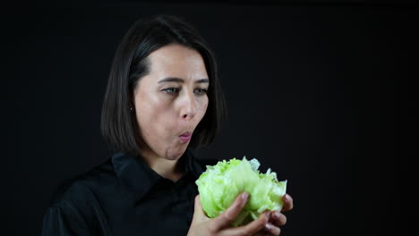 young woman biting cabbage, vegan diet and healthy food concept, black background