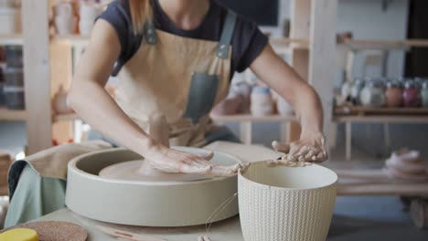 female potter works with clay on the pottery wheel.