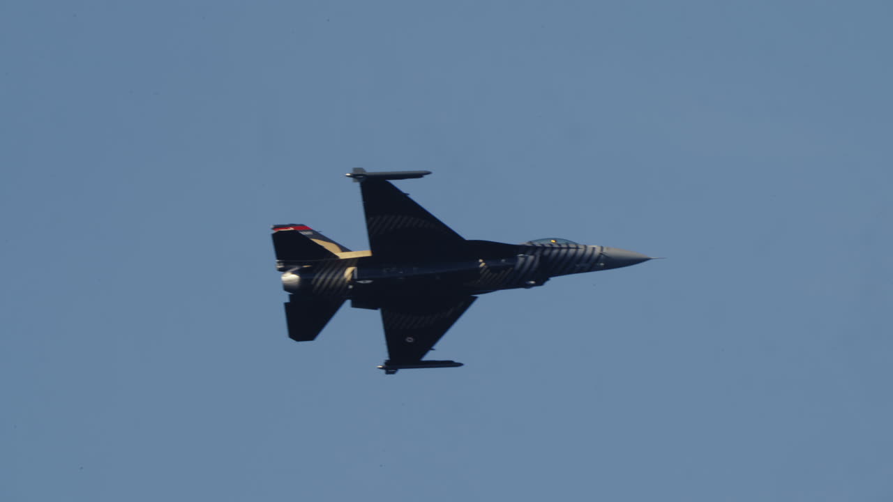 Jet Tempur F-16 Hitam dan Emas Terbang di Langit Biru