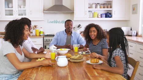 Family-With-Teenage-Children-Eating-Breakfast-In-Kitchen