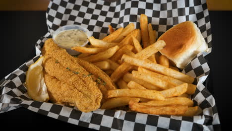 Fried-catfish-platter-with-seasoned-fresh-cut-french-fries-on-checkered-paper,-slider-4K