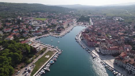 Boats-docked-along-port-of-Stari-Grad-Hvar-island,-Croatia,-aerial-establishing-overview