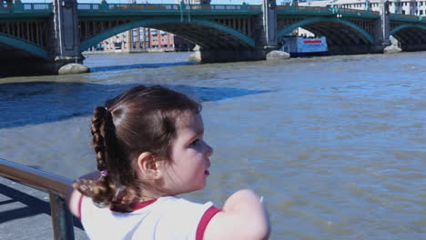 a child looks out at the thames river while waving, with st. paul's cathedral visible in the background