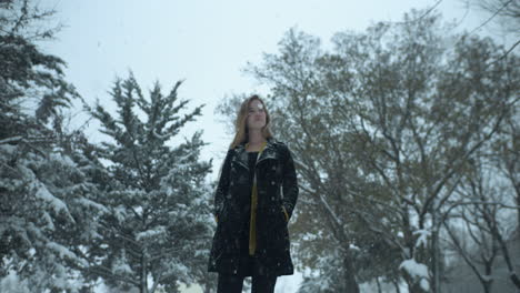 happy woman outside in slow motion winter snow as snowflakes fall in cinematic slow motion