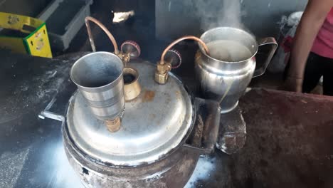 tandoori chai in india - spicy milk tea being poured over a hot terracotta cup straight from the tandoori oven - tandoor tea in making