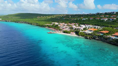 aerial dolly establishes deep vibrant blue gradient water and reef and beautiful white sand beach on sunny day