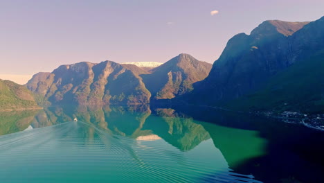 A-boat-crossing-a-fjord-in-Norway-with-the-mountains-and-sky-reflecting-off-the-water