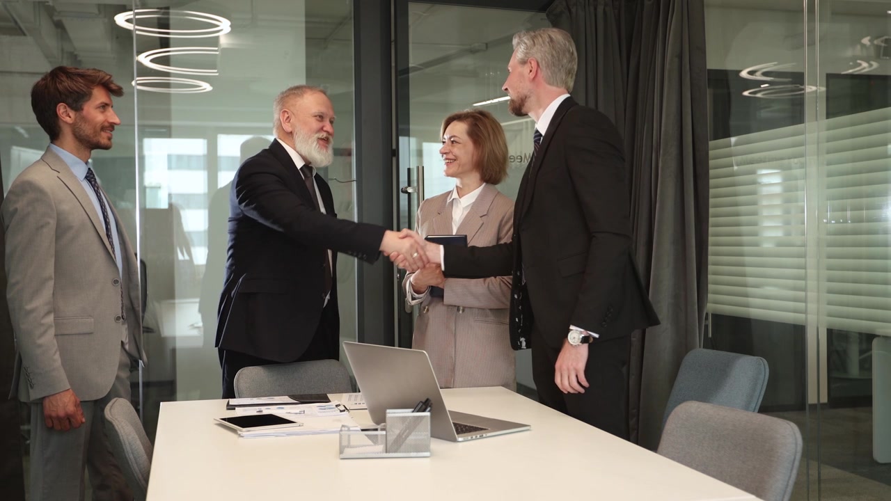 Professionisti del settore business che si stringono la mano durante una riunione d'ufficio.