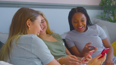 Grupo-De-Amigas-Adolescentes-Multiculturales-Con-Teléfonos-Móviles-Colgando-En-El-Dormitorio-En-Casa