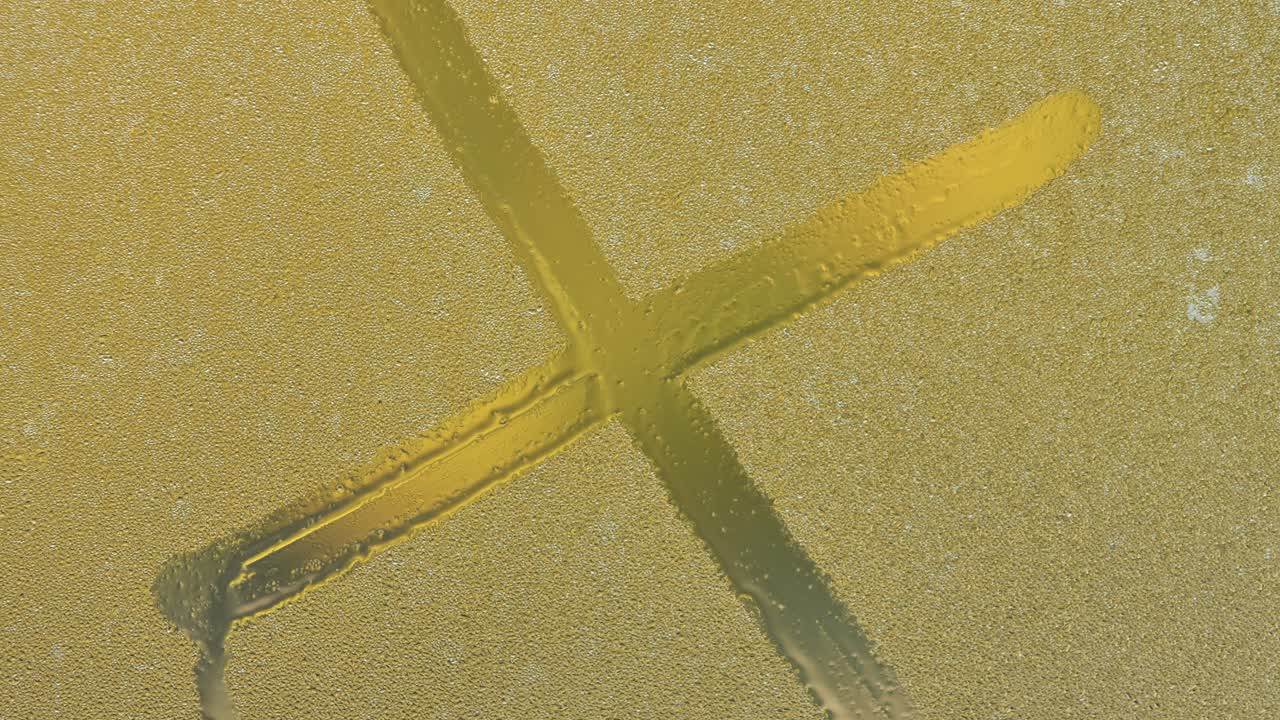 A large letter X drawn on a foggy window