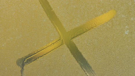 a large letter x drawn on a foggy window