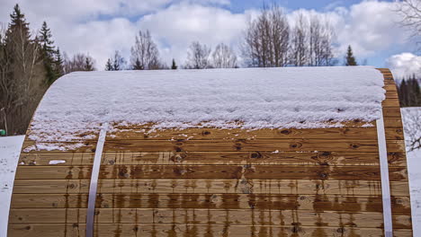 melting snow on top of thermowood wooden barrel sauna, timelapse