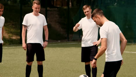 a young soccer man training freestyle tricks on a street football pitch while his team watching him 1