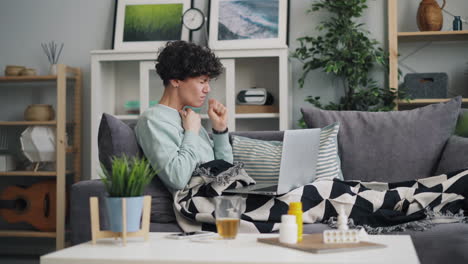 sick person on couch with laptop