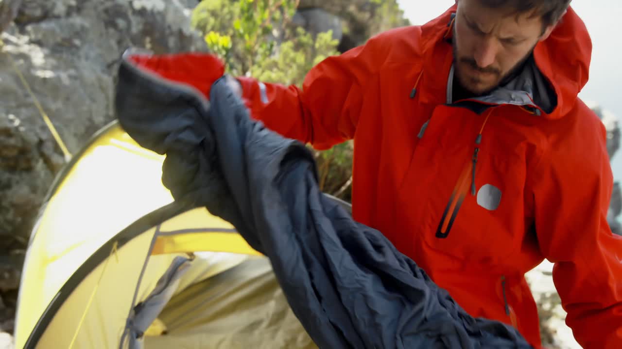 excursionista masculino de pie cerca de la tienda en el campo 4k