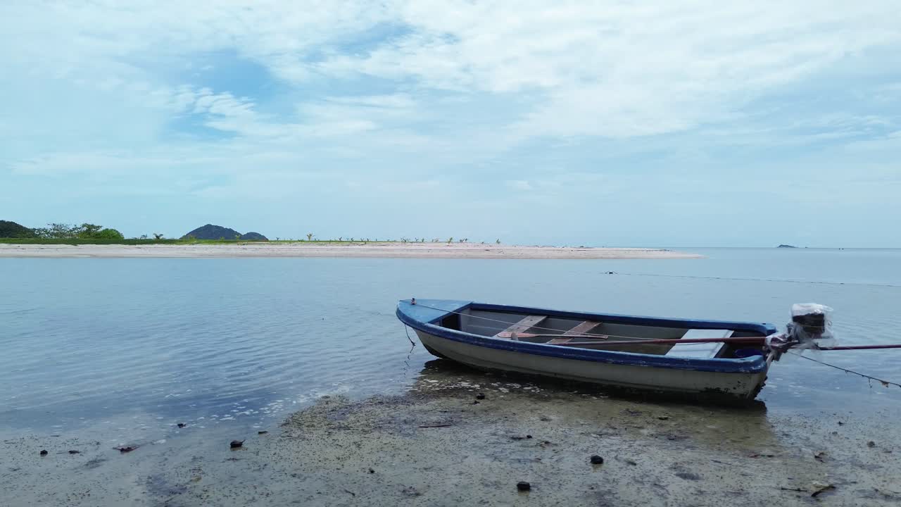 Drone video shows traditional small fishing boats anchored near the sandy shoreline of Koh Phangan, Thailand, with clear turquoise water and lush green coastline creating a scenic tropical seascape