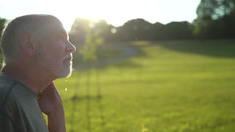 Slow-motion-sunny-scene-of-man-sneezing-showing-aerosol-using-water-hose