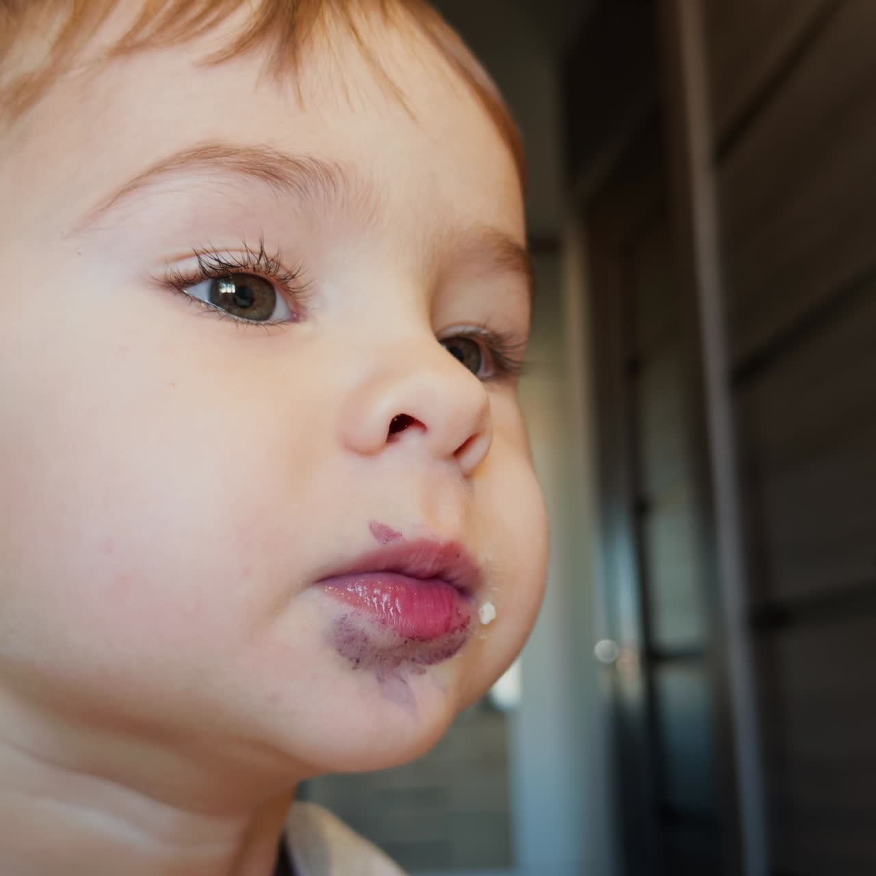 Volto di un adorabile bambino con macchie intorno alla bocca. Il bambino apre la bocca parlando. Primo piano