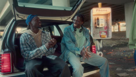 black friends chatting as hanging out by car under overpass