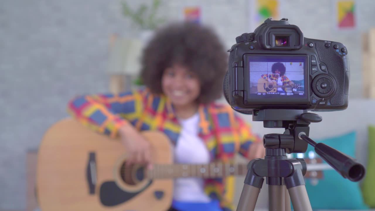 blogger mujer afroamericana con un peinado afro con una guitarra la vista a través de la pantalla de la cámara