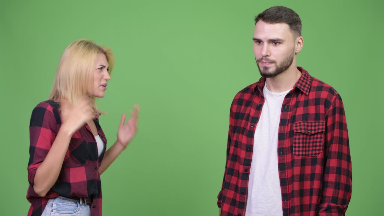 Young woman fighting young man against green background