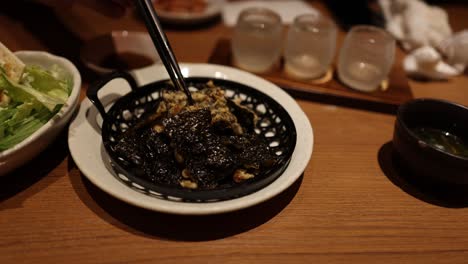 person eating black curry with rice and salad