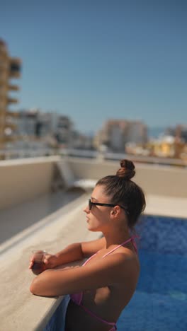 woman relaxing by the rooftop pool in a pink bikini