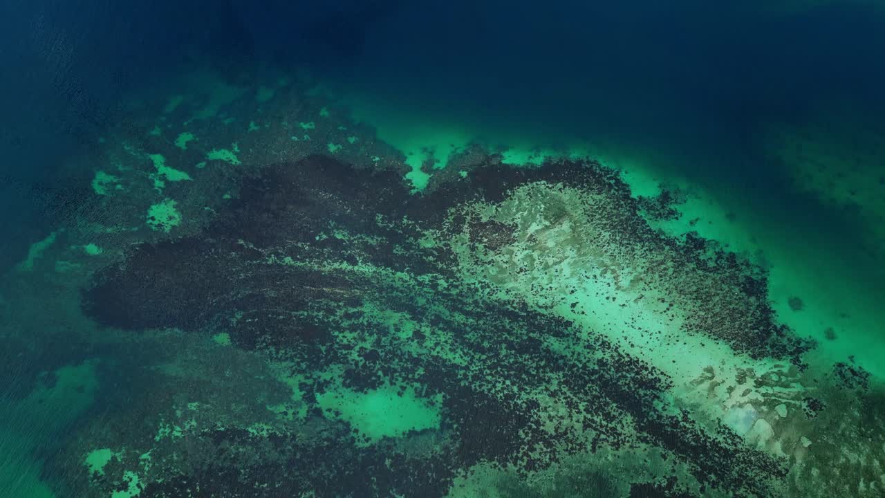 Drone flies over the shallow turquoise waters approaching Magalawa Island, highlighting the beach shoreline and tropical scenery