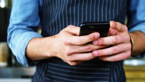 Male-waiter-using-mobile-phone