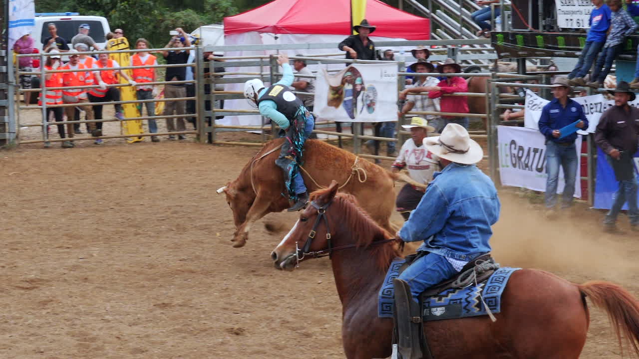 Bull rider competes at Foire de Bourail rodeo, Grande Terre, New Caledonia. Slow motion.