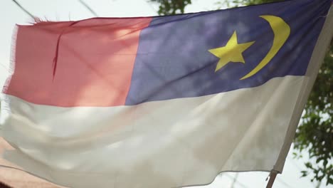 eine wehende melaka-flagge mit baum und blauem himmel im hintergrund
