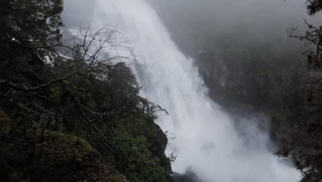 tilt down shot of mystic waterfall crashing down in rainforest, slow motion