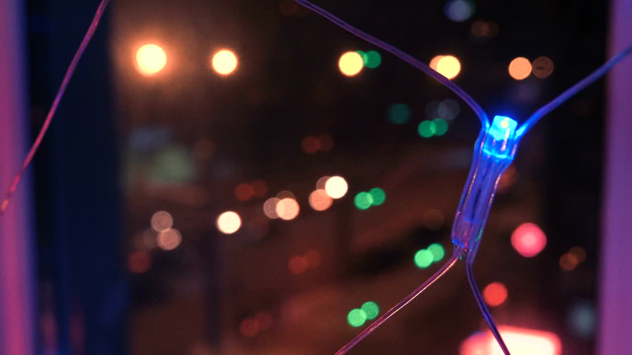 рождественская гирлянда с красочными огнями у окна на фоне города и движения автомобилей, крупный план. размытые рождественские огни. боке.