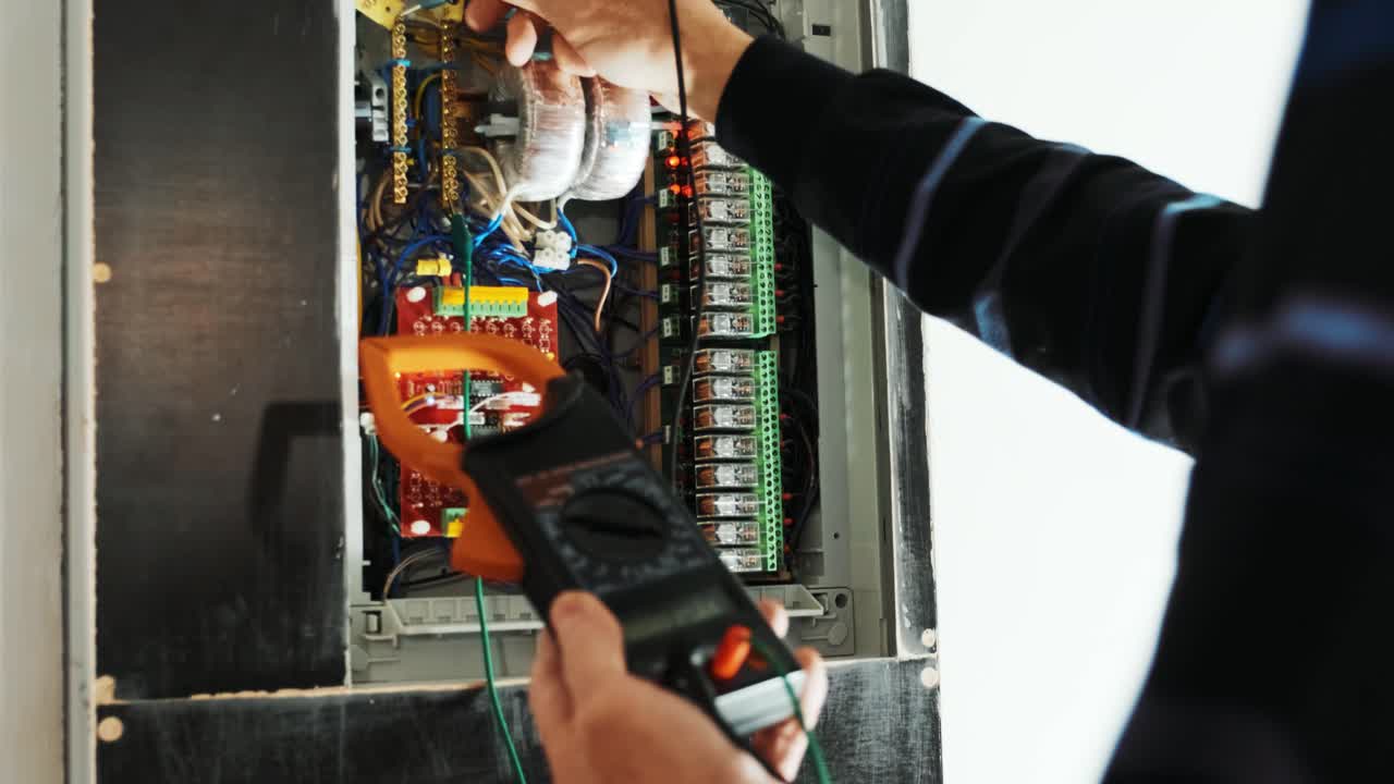 los electricistas ponen las manos a probar la corriente eléctrica en el panel de control. el ingeniero electricista trabaja midiendo el voltaje y la corriente de la línea eléctrica en el control del gabinete eléctrico.