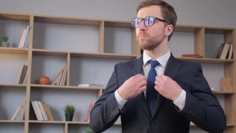 a businessman in glasses fastens his jacket he looks away a businessman in glasses fastens his jacket he looks away portrait of a manager in the office business people concept
