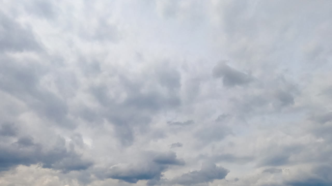 Clouds covering the sky at daytime. Grey cloudscape in the atmosphere from low angle view. Timelapse.