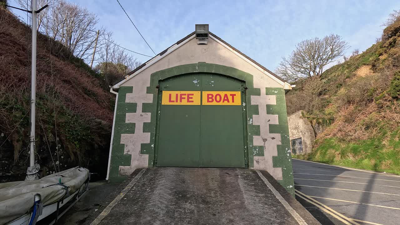 Lent panoramique vers le haut : garage à bateaux de sauvetage avec rampe sur la côte de Tramore, Irlande