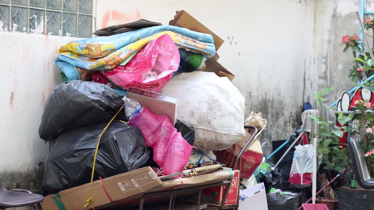 한 사람 이 과부하 된 바구니 에서 쓰레기 봉투 를 내린다