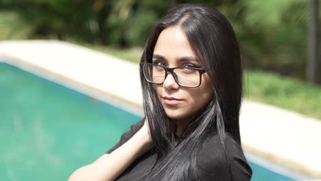 beautiful green eyed latina woman with glasses sitting poolside