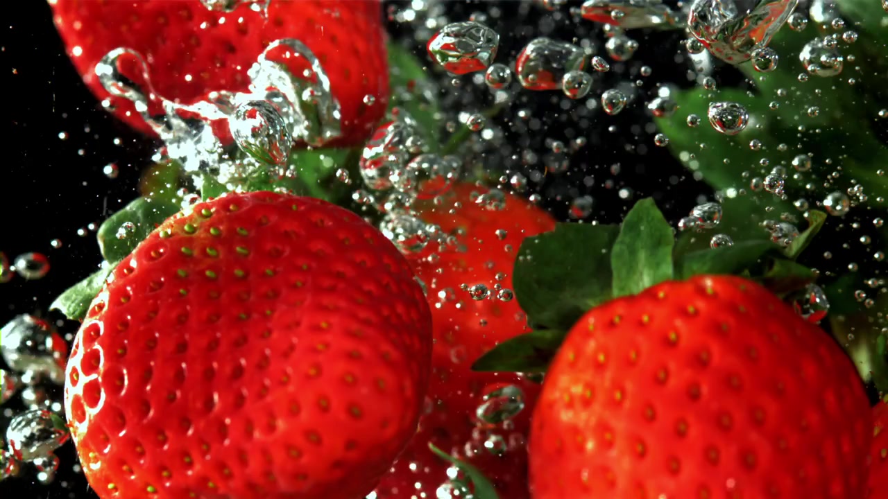 Fragole rosse che schizzano nell'acqua al rallentatore