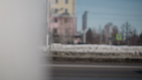 blur highway view shows bus and cars moving side by side in winter light, window reveals passengers, dirty wheel spinning, city commute mood, snow by curb, soft focus motion, passing traffic rhythm