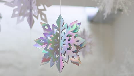 Holographic snowflakes rotate gracefully, suspended against a soft, blurred background, creating a serene and festive atmosphere.