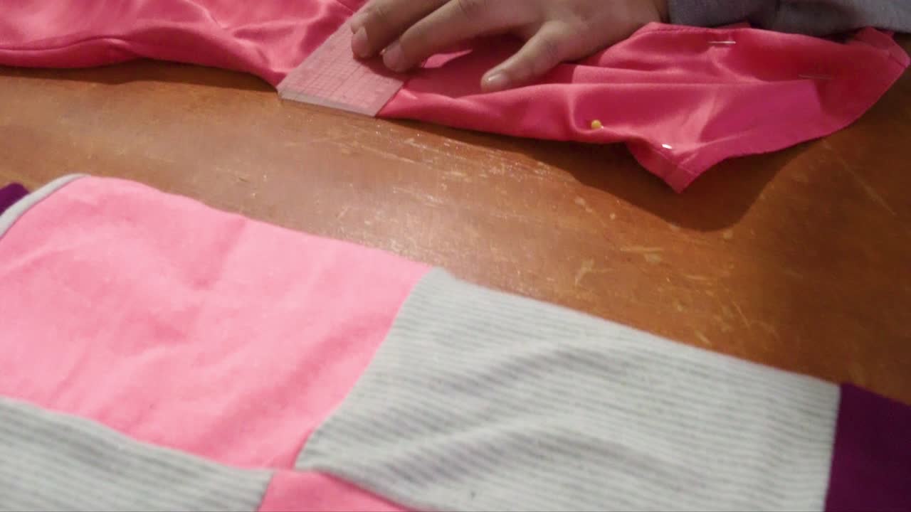 cerca de una costurera latina manos marcando un vestido con una tiza blanca y una regla curva