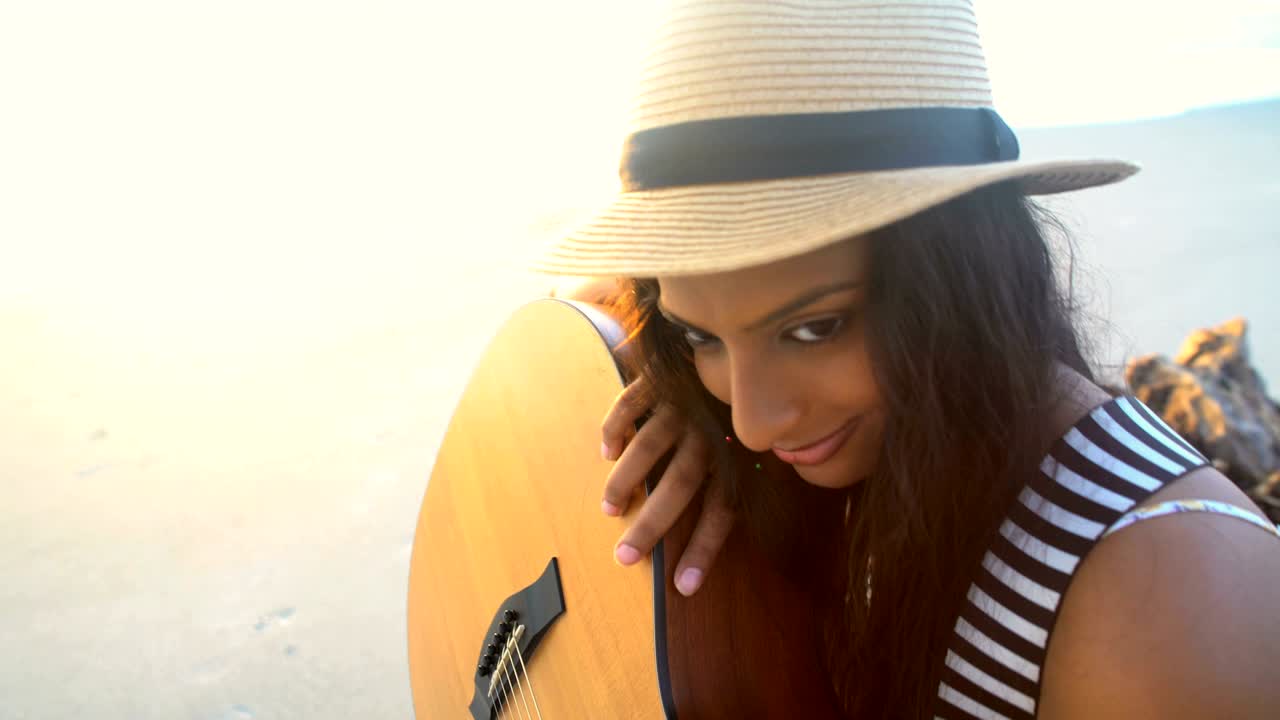 mujer india asiática descansando en la playa con una guitarra