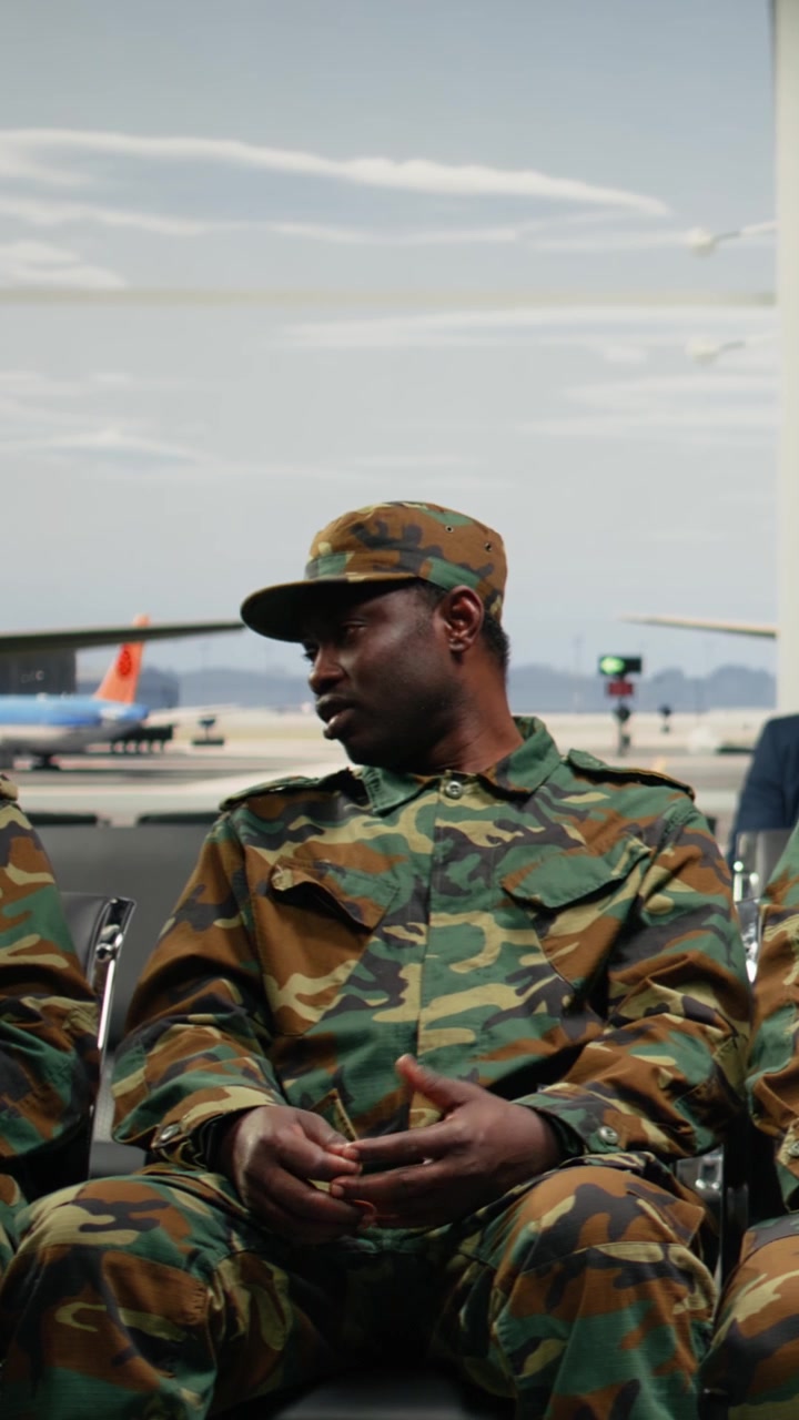 Video verticale: Soldati dell'esercito multietnico che chiacchierano in aeroporto, in attesa che si apra il gate d'imbarco.