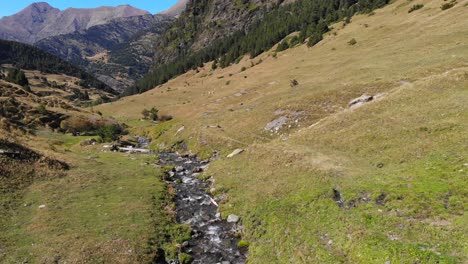 aerial: valley with a small stream among high peaks in the pyrenees