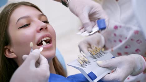 woman in stomatological cabinet. professional stomatologist holding dental crown for female patient