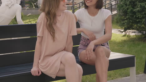 two women friends chatting on a park bench