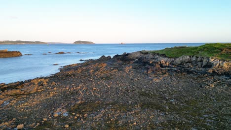 Toma-Panorámica-De-La-Costa-Noreste-De-Guernsey-A-Través-Del-Canal-Little-Russell-Hasta-Herm-Y-Jethou-Y-Vista-De-St-Sampson-A-Distancia-Con-El-Castillo-De-Vale-Sobre-La-Costa-Rocosa