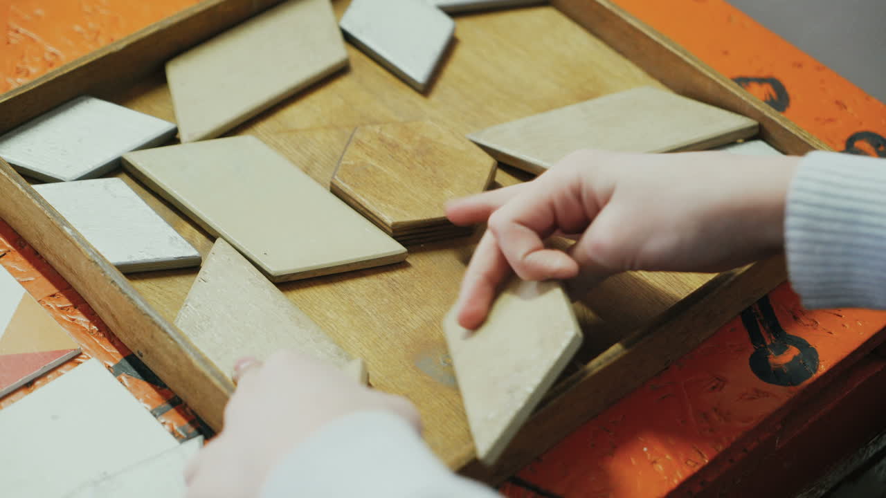 Close-up, hands of a child playing with a wooden puzzle. Concept of education.